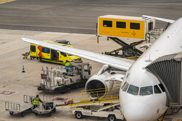 Passenger aircraft parked on airport apron while ground crew operate service vehicles duri © JairoMZ