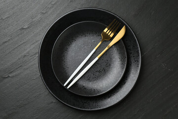 Stylish setting with cutlery on black table, top view