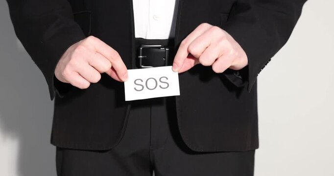 Urology. Man holding note with word SOS on grey background, closeup. Camera moving down