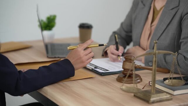 A young, professional Asian female lawyer is advising and consulting female clients, discussing legal contracts and women's rights in the office.