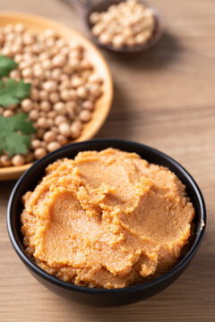 Traditional Japanese miso paste in a black bowl on a rustic wooden table. Healthy fermented soybean seasoning for cooking