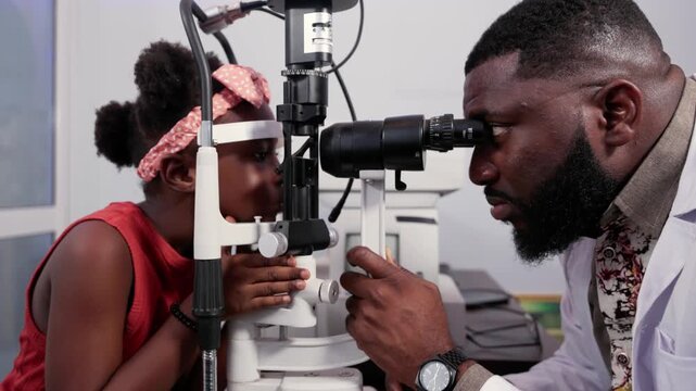 Optometrist conducting a vision checkup on African child using slit lamp in a clinic