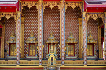 Obraz premium Intricate wall pattern and ornate window details of a Thai temple.