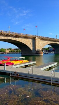 London Bridge in Lake Havasu City, Arizona, USA, featuring the original masonry built in 1830s in London, England. British flags flying above the posts, with boats docked at Bridgewater Channel Canal
