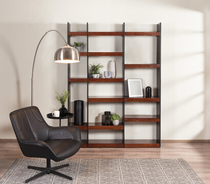 Industrial-chic reading corner with a black swivel accent chair, tall open bookshelf with walnut shelves, and a sleek metal arc floor lamp, set on warm wood flooring for a stylish interior vibe.