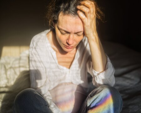 Pregnant woman sitting on a bed with hand on head feeling tired or stressed, moody indoor scene capturing maternity struggle and mental health concept for healthcare