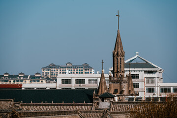 Obraz premium A distant perspective of the Catholic Church nestled within Qingzhou Ancient City. The church stands gracefully amid traditional Chinese architecture, showcasing a blend of Eastern & Western cultures.