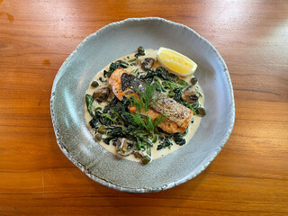 Pan-seared Salmon Steak served in a rich white cream sauce with fresh sauteed spinach