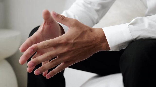 Close up of nervous businessman hands fidgeting fingers while sitting indoors. Concept of anxiety stress waiting tension or uncertainty in business situation.