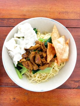 Indonesian Bakso Meatball Noodle Soup in White Bowl on Wooden Table