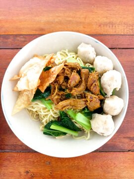 Indonesian Bakso Meatball Noodle Soup in White Bowl on Wooden Table