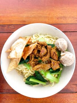 Indonesian Bakso Meatball Noodle Soup in White Bowl on Wooden Table