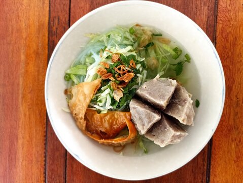 Indonesian Bakso Meatball Noodle Soup in White Bowl on Wooden Table