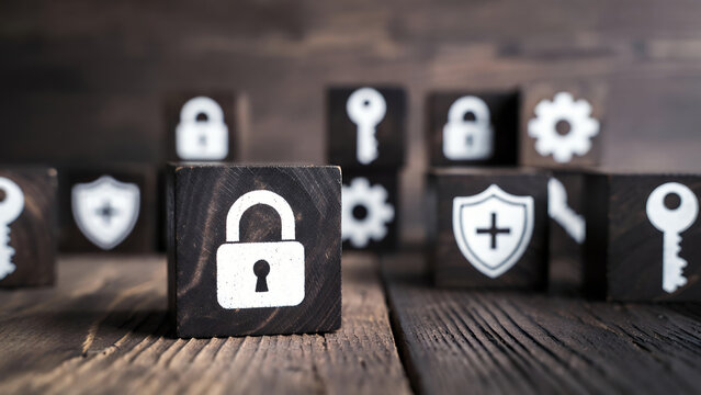Close-up of dark wooden blocks featuring cybersecurity icons such as padlock, shield, and key.
