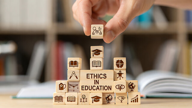 A hand places a wooden block with icons on top of 'Ethics in Education' blocks.