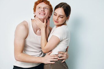 Fototapeta premium Young couple embracing and smiling with affection, woman gently holding man’s face, studio portrait with casual clothing and light background for relationship concept.