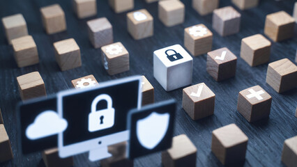 Cybersecurity concepts are illustrated with a monitor displaying icons among numerous wooden cubes.