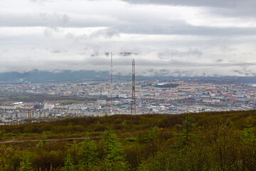 Obraz premium A summer view from a mountainside of a large northern city. Overcast and low clouds. Magadan, Magadan Oblast, Russian Far East.