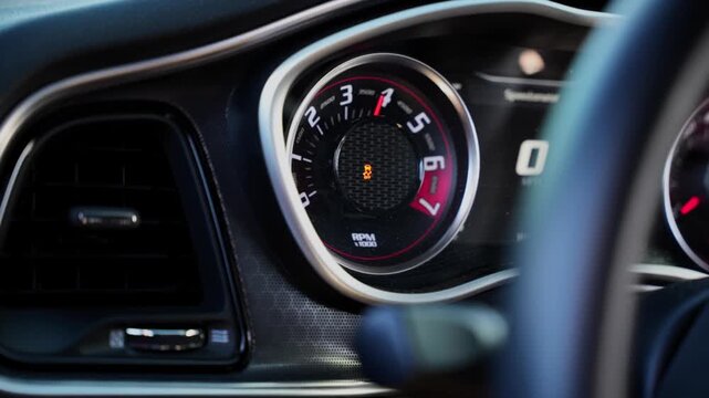 High performance sports car tachometer needle rising as the motor revs in neutral. Dodge Challanger - american muscle car.