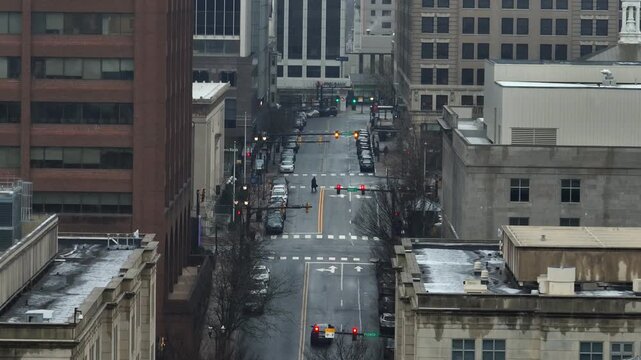 Aerial view of downtown Wilmington, Delaware with winter traffic moving along city street between historic buildings and a brick clock tower. Descend wide shot. Cold winter time in USA.