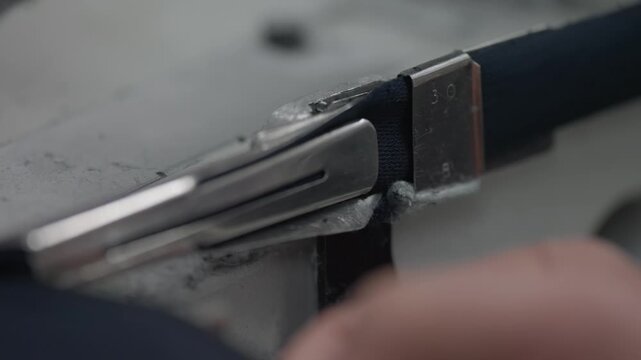 Close up of coverstitch sewing machine guiding fabric edge through metal binder