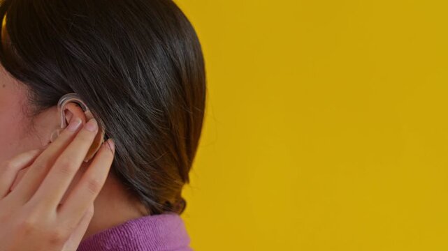 Side view showing woman adjusting her modern hearing aid