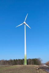 Fototapeta premium Wind power generator isolated against clear blue sky. Modern renewable energy infrastructure and clean electricity production concept.