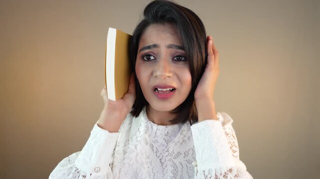 Close up headshot of sad unhappy young South Asian woman student girl holding notebook look at camera feels stress anxiety study pressure, isolated against grey studio backdrop or background.