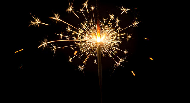 Handheld sparkler firework emitting bright golden sparks against a solid black background