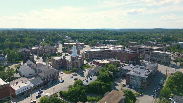 Slow drone orbit shot of historic Dover City Hall in Dover, NH, USA. It shows light traffic and red brick buildings on a bright summer afternoon.