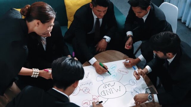 Top view of skilled diverse business people planning project by using mind map to brainstorm marketing idea. Smart start up team working together to draw mind map. Creative workplace. Directorate.