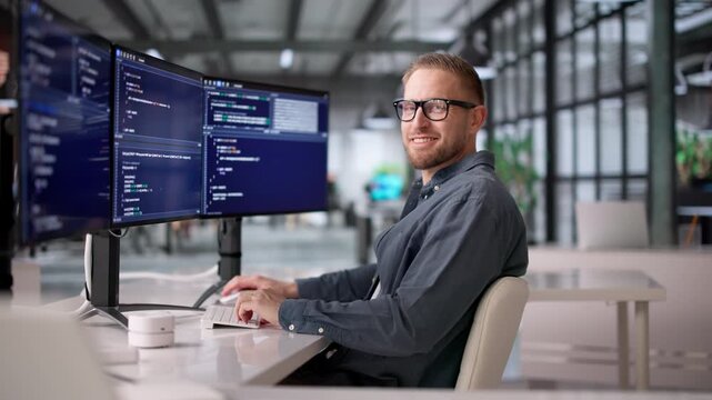 Computer Programmer Happily Writes Software Code Using Multiple Monitors