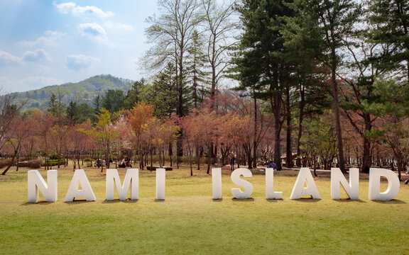 Nami Island white sign, which is surrounded by trees and mountains