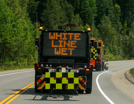 Canada, BC, Valemount.  Road crew painting line on the side of highway 5 in mountainous terrain.