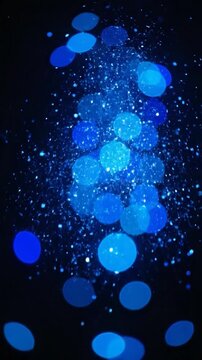 Abstract blue bokeh lights and glitter on a dark background