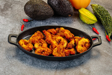 Crispy fried calamari rings appetizer on a plate with fresh chili and avocado.