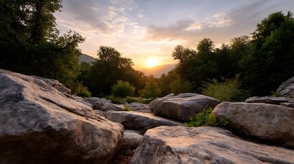Warm golden hour sunset illuminating a serene rocky landscape surrounded by lush green forest and soft clouds