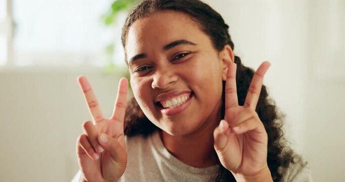 Face, smile and woman with peace sign in home on weekend, confidence and positive attitude for day off. Portrait, free time and happy person with emoji for wellness, gesture and dancing in apartment