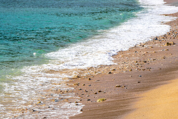 Clear turquoise blue waves water pebbles rocks beach sand Thailand. © Arkadi