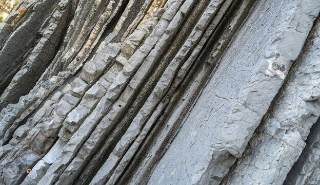 Layered rocks, flysch texture background. Sedimentary rock, striations stone pattern