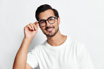 Smiling man wearing glasses and a white t-shirt, looking at the camera while adjusting his glasses...