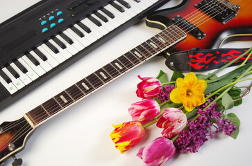 Fototapeta premium Synthesizer keyboard, electric guitar, bouquet of tulips and daffodils
