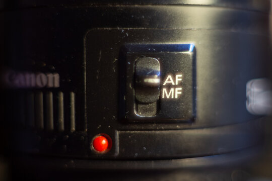 A detailed view of canon lens focusing switch with red indicator light for professional photography equipment
