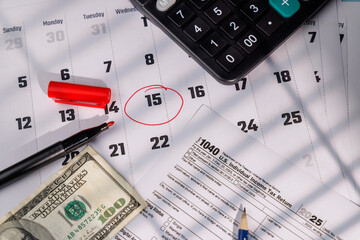 Tax Day deadline with a red circle on 15 and IRS Form 1040 near a hundred dollar bill and a calculator for accounting concepts.