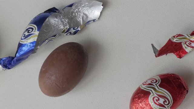 Chocolate Easter eggs with wrappers on a light background, sweet treats