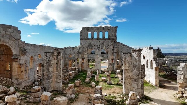 Close-up drone shot of the majestic 5th-century Saint Simeon Stylites church ruins in Syria, featuring preserved Byzantine arches and ancient stone masonry