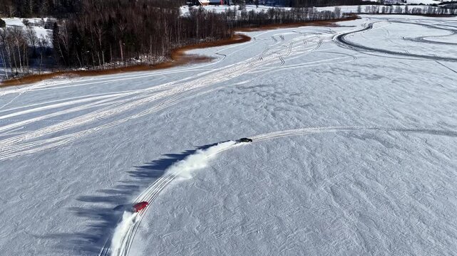 Drone tracking cars drifting on fresh snow, wintry landscape in Latvia - aerial 4k