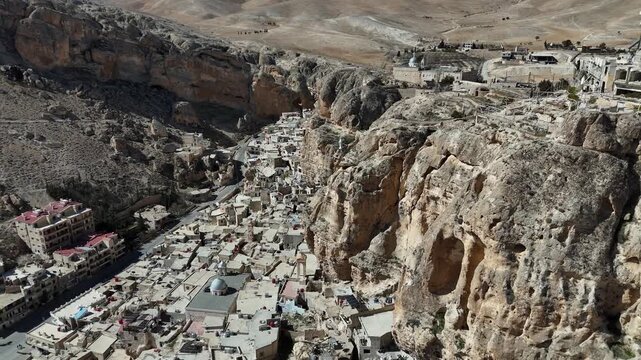 High-angle perspective of the historic village of Ma'loula, Syria, highlighting its dramatic location within the Qalamoun Mountains