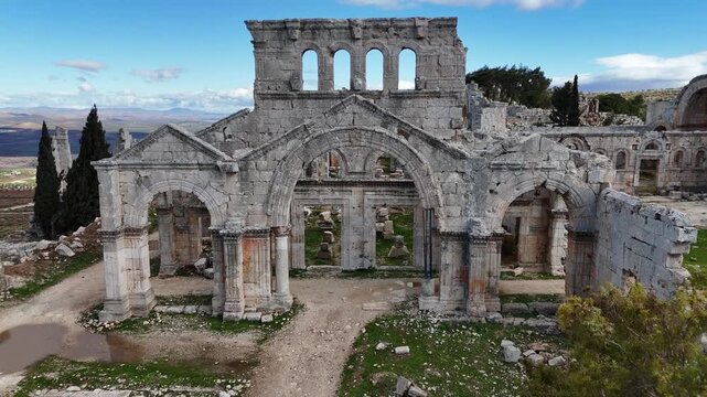 Close-up drone shot of the majestic 5th-century Saint Simeon Stylites church ruins in Syria, featuring preserved Byzantine arches and ancient stone masonry, POV entering the gate
