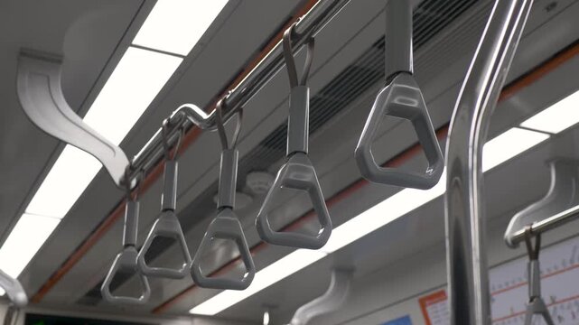 Slow motion close up of plastic passenger handles hanging from a railing inside transit commuter subway train carriage providing stability for standing riders in Seoul city South Korea urban transport